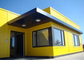 Malá výrazná administrativní budova žluté barvy s modrými prvky